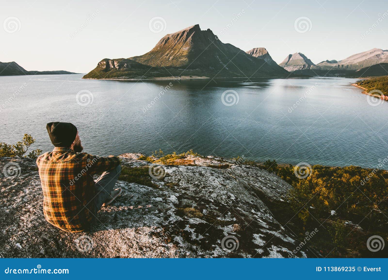 man sitting alone enjoying sea and mountains view