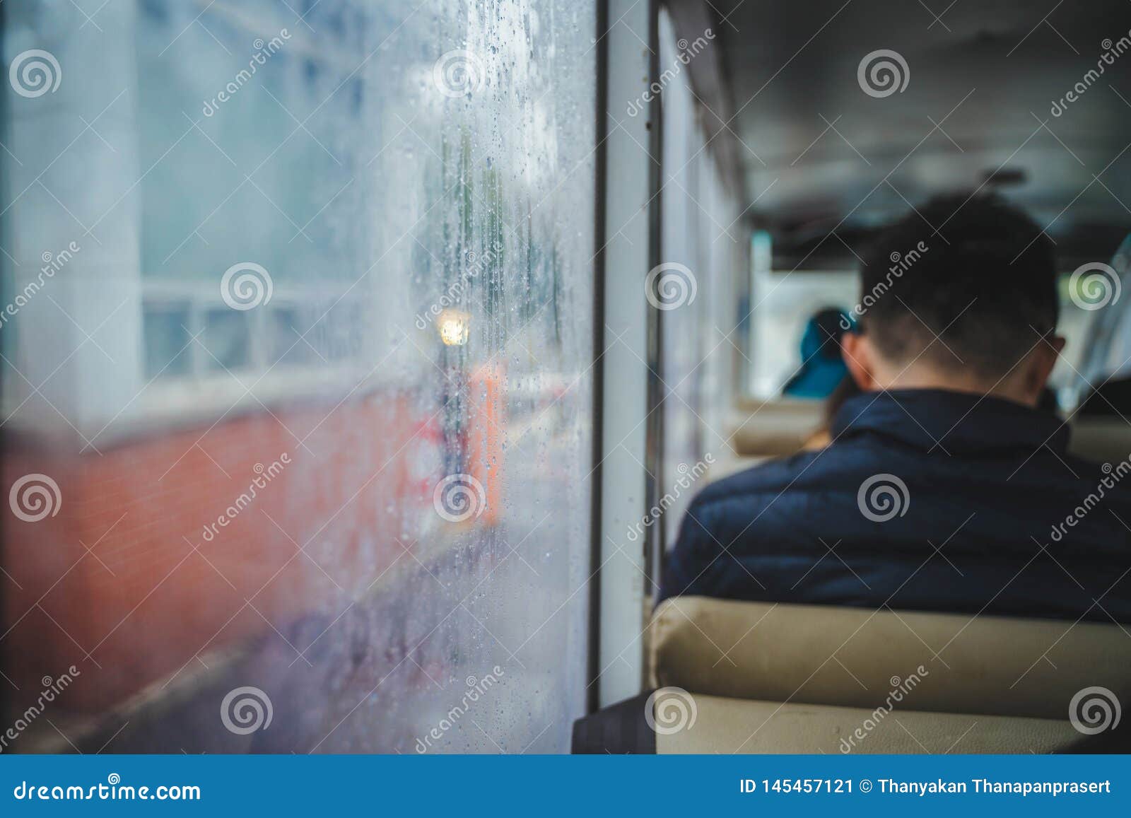 A Man is Sitting on the Bus Near a Glass Window with Steam Stock