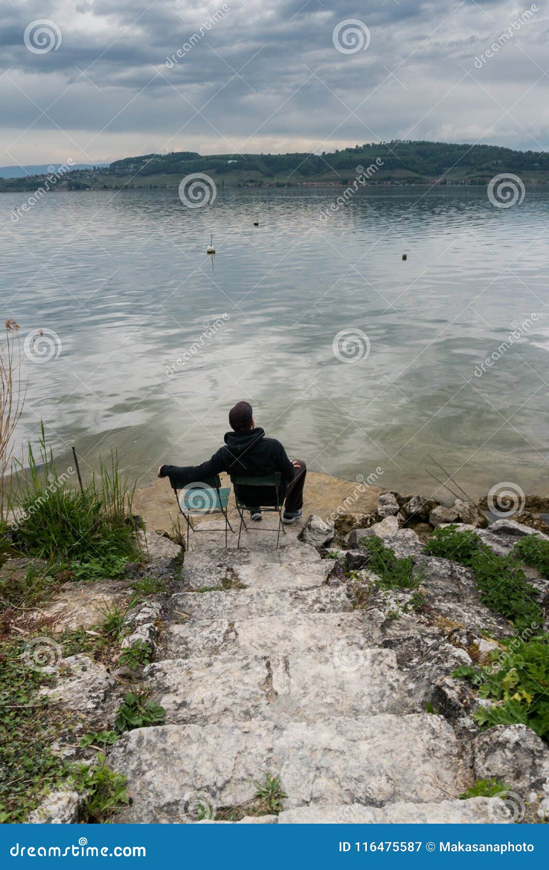 Man Sitting On A Chair At The Shores Of A Beautiful Lake On
