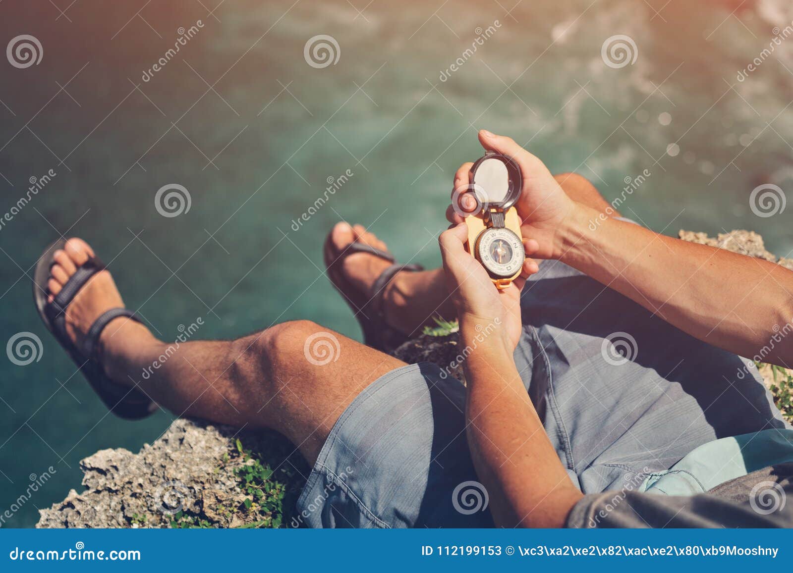 Man Sitting with Compass Above the Ocean on Cliff Stock Image Image
