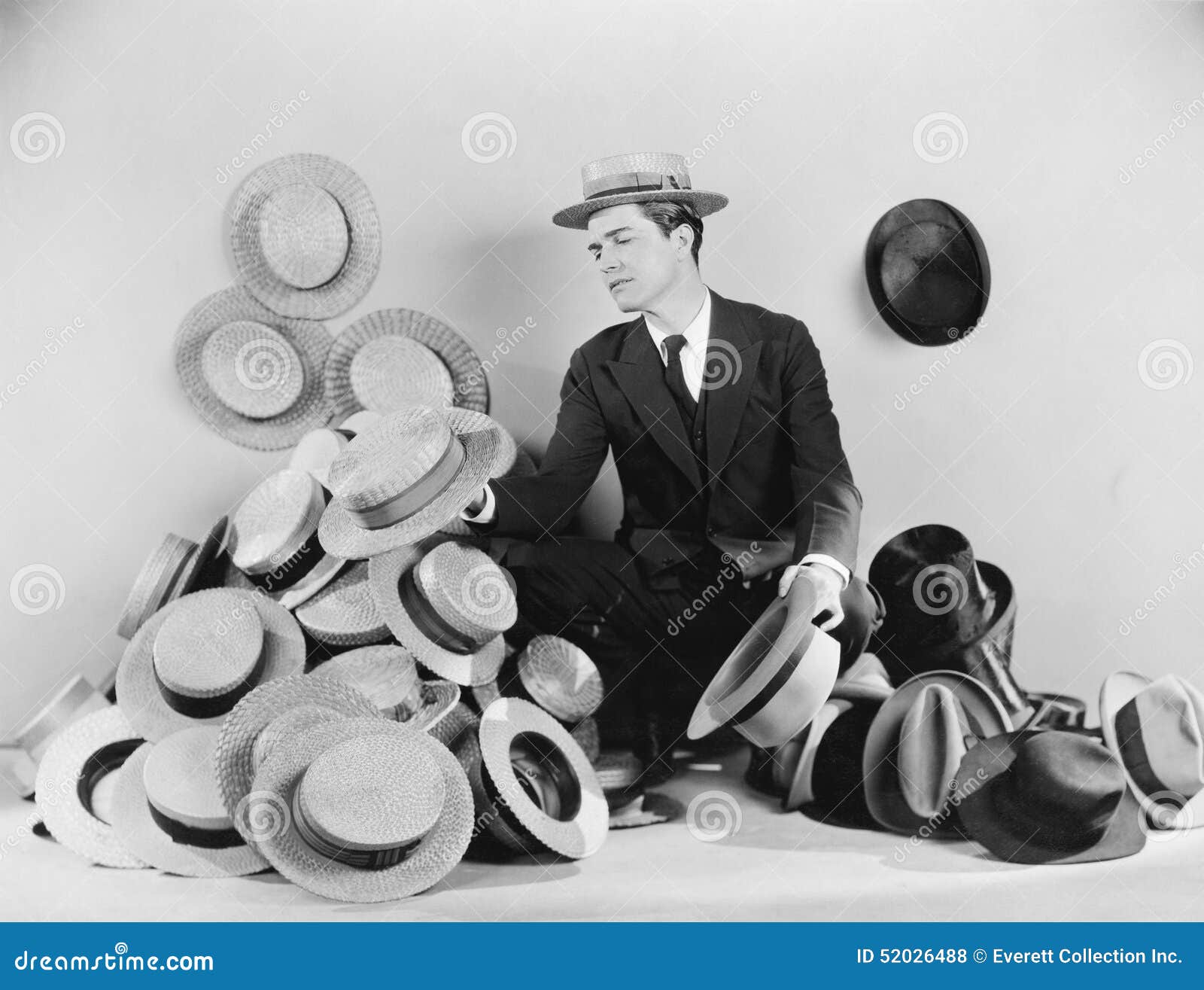 man sitting on the floor surrounded by hats