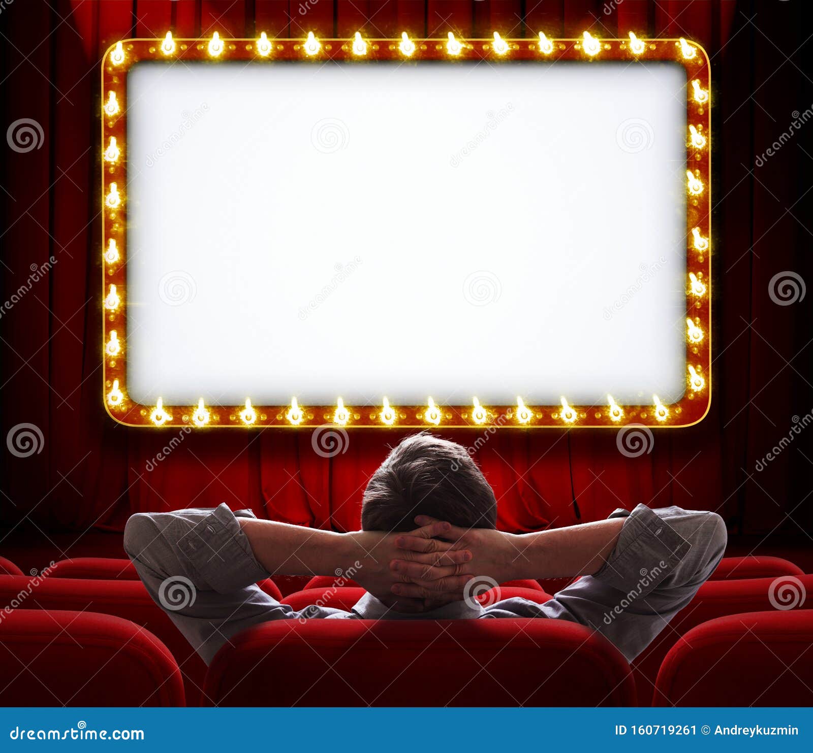 man sitting in front of lighted sign on red theatre curtain