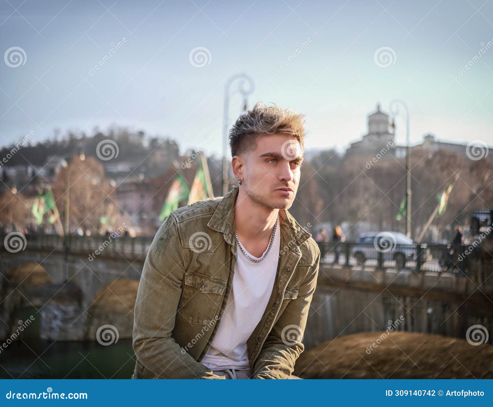 man sitting on ledge in front of bridge