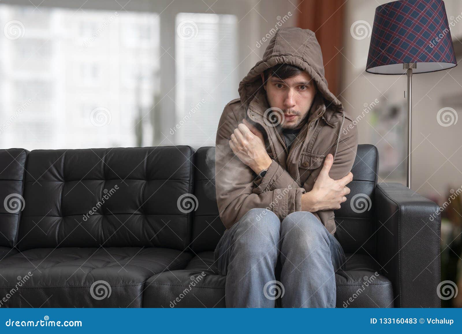 man is sitting on sofa at home and feeling cold.