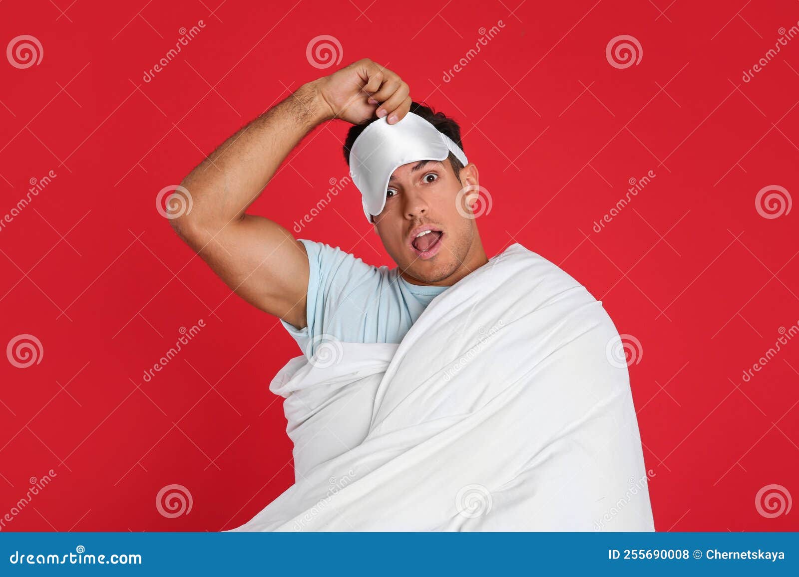 Man in Sleeping Mask Wrapped with Blanket on Red Background Stock Photo