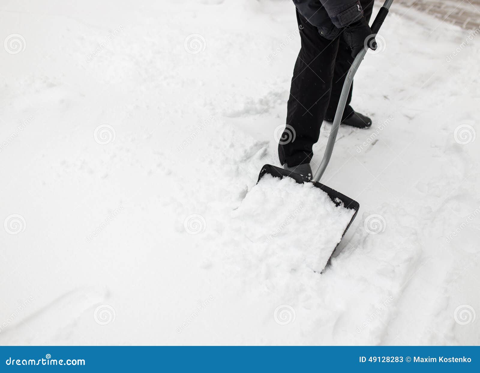 man with snow shovel cleans sidewalks