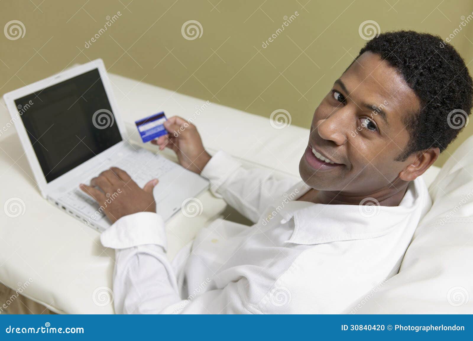 Man on Sofa Using Credit Card To Make Purchase with Laptop Portrait