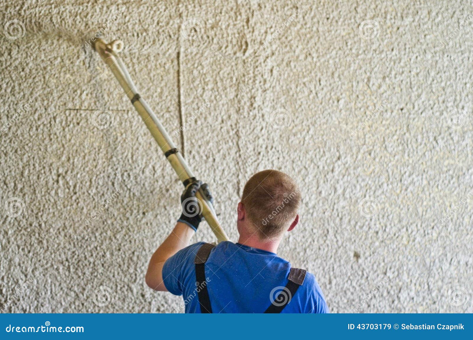 man spraying concrete stucco to wall