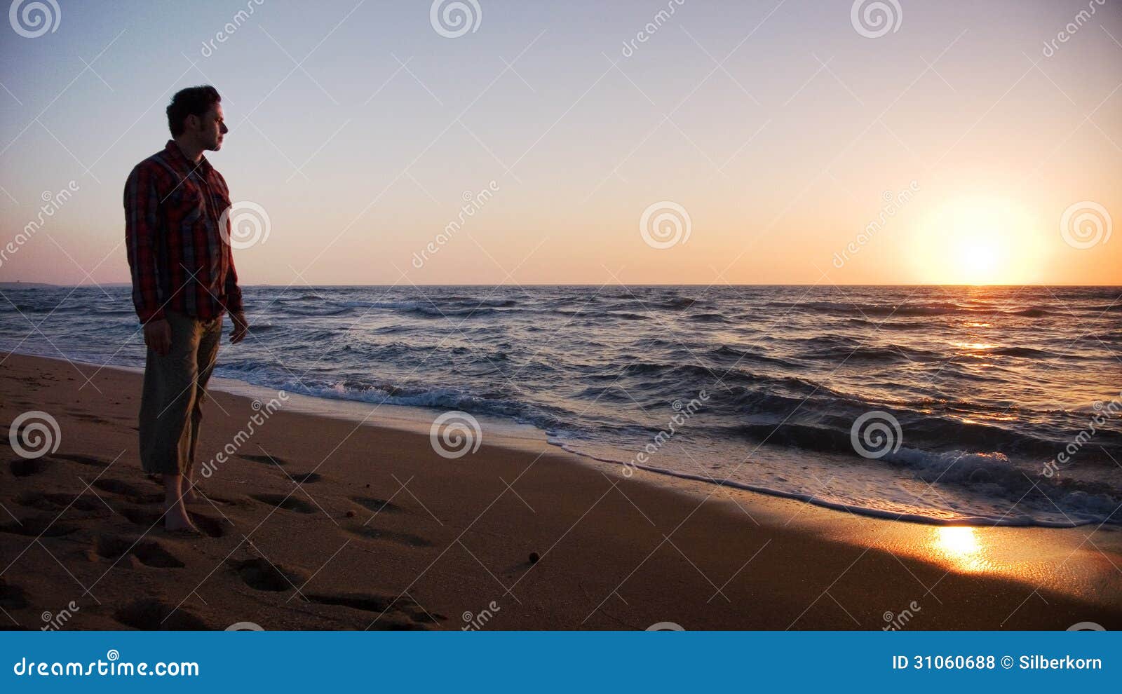 Man Standing On The Beach And Looking Into Sunset Stock Photo Image