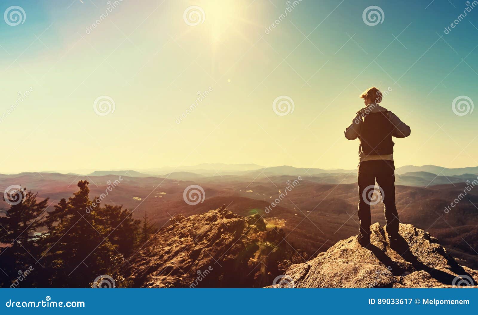 man standing at the edge of a cliff overlooking the mountains