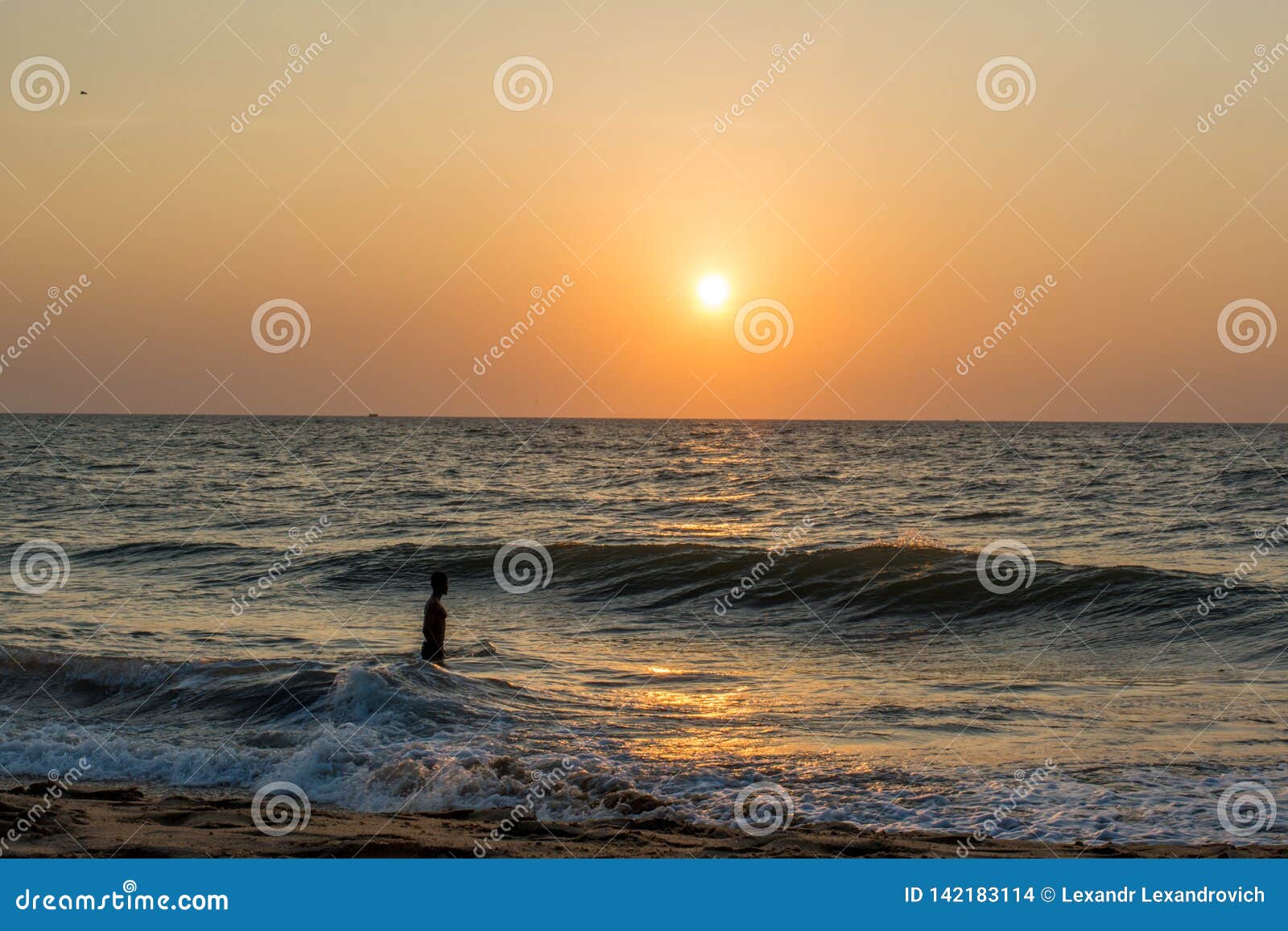 A Man Standing in the Ocean on the Beach during Sunset Stock Photo ...
