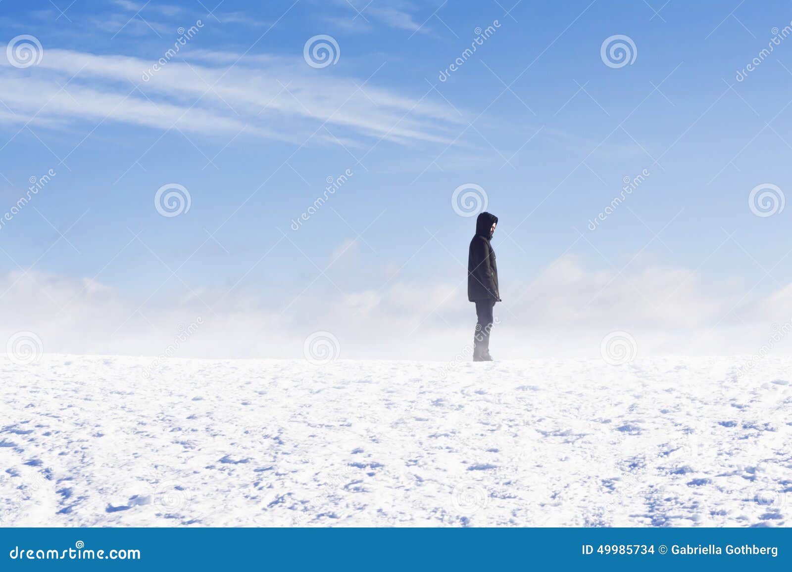 Man standing in snow flurry against blue sky. Man standing on a mountain in snow flurry against blue sky.
