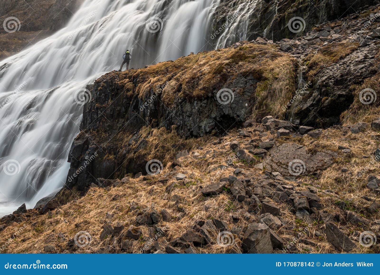 man stands infront of dynjandi or fjallfoss,  big and powerfull waterfall cascade in the westfjords