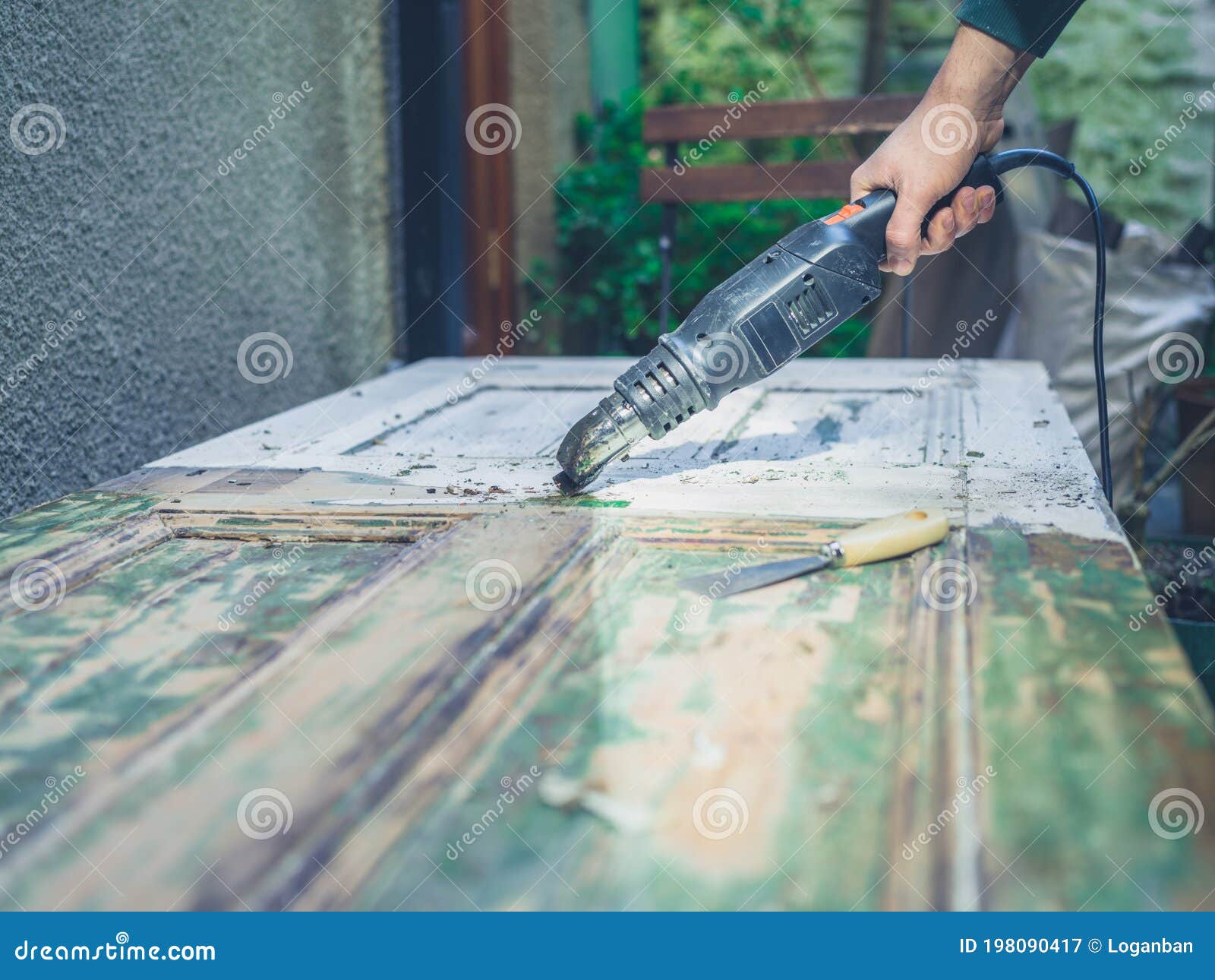 man stripping paint with heat gun