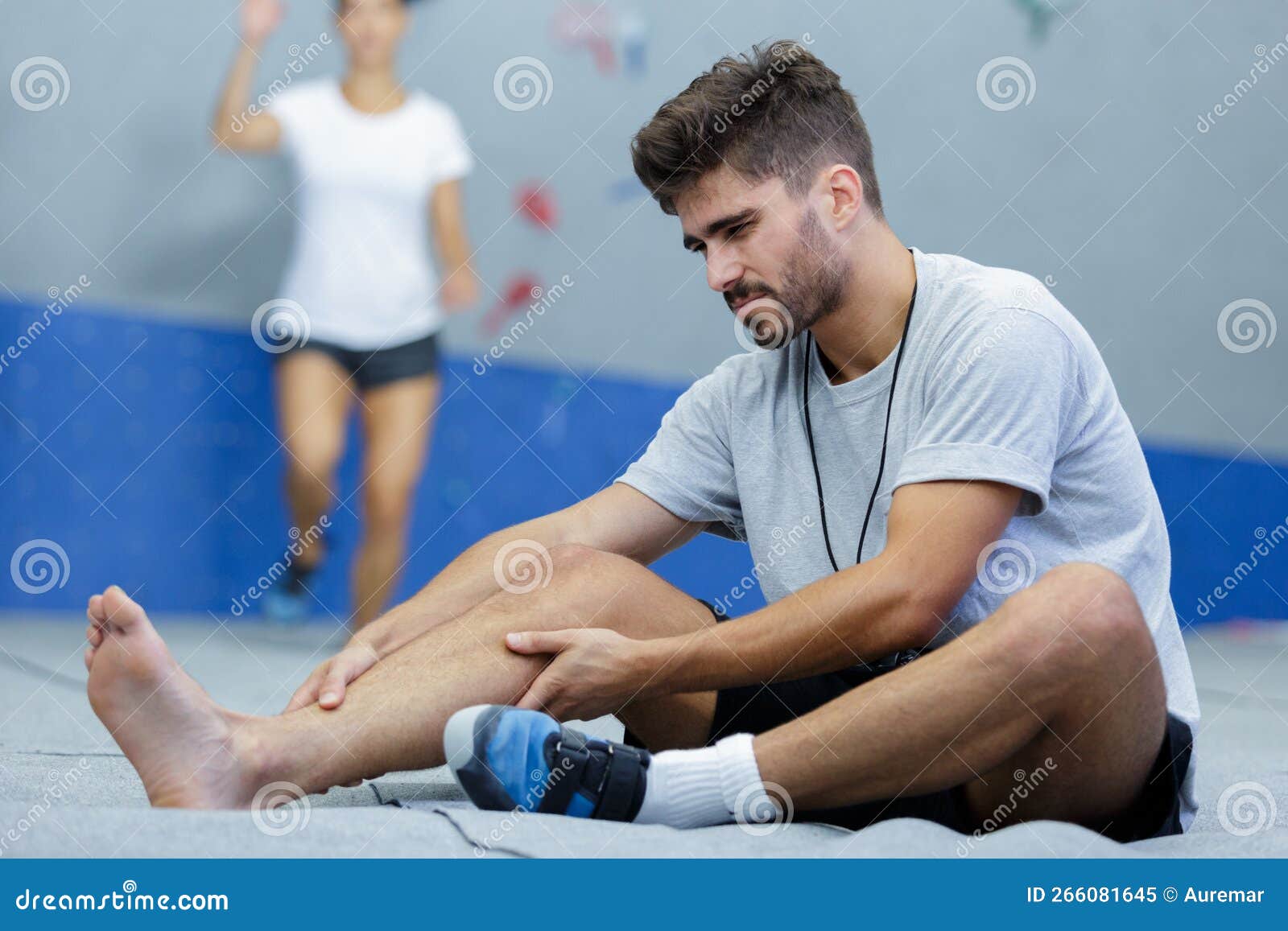 Man Suffering from Pain in Leg while Sitting on Floor Stock Image