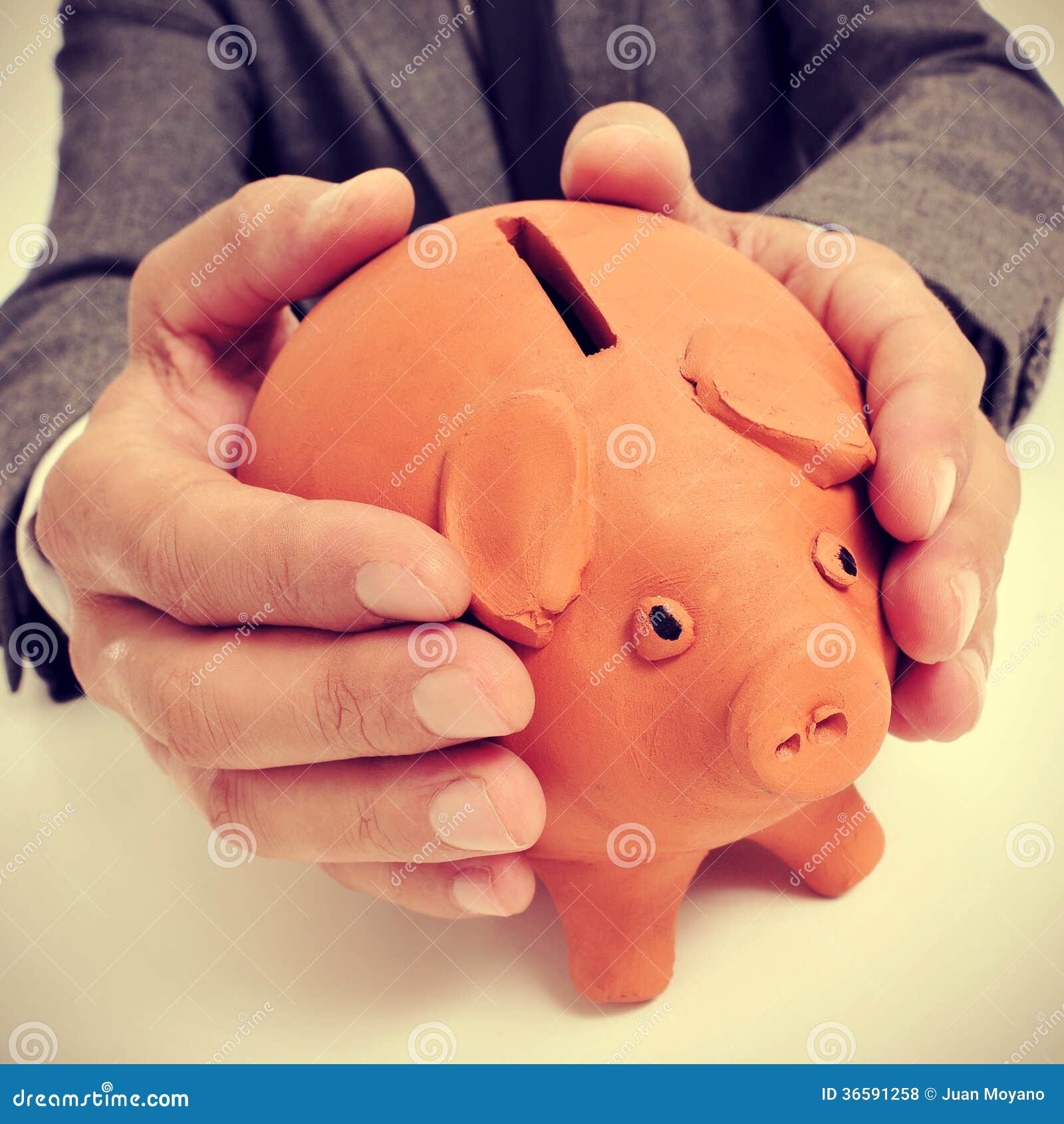 Man in suit with a piggy bank. A man wearing a suit sitting in a desk with a piggy bank in his hands