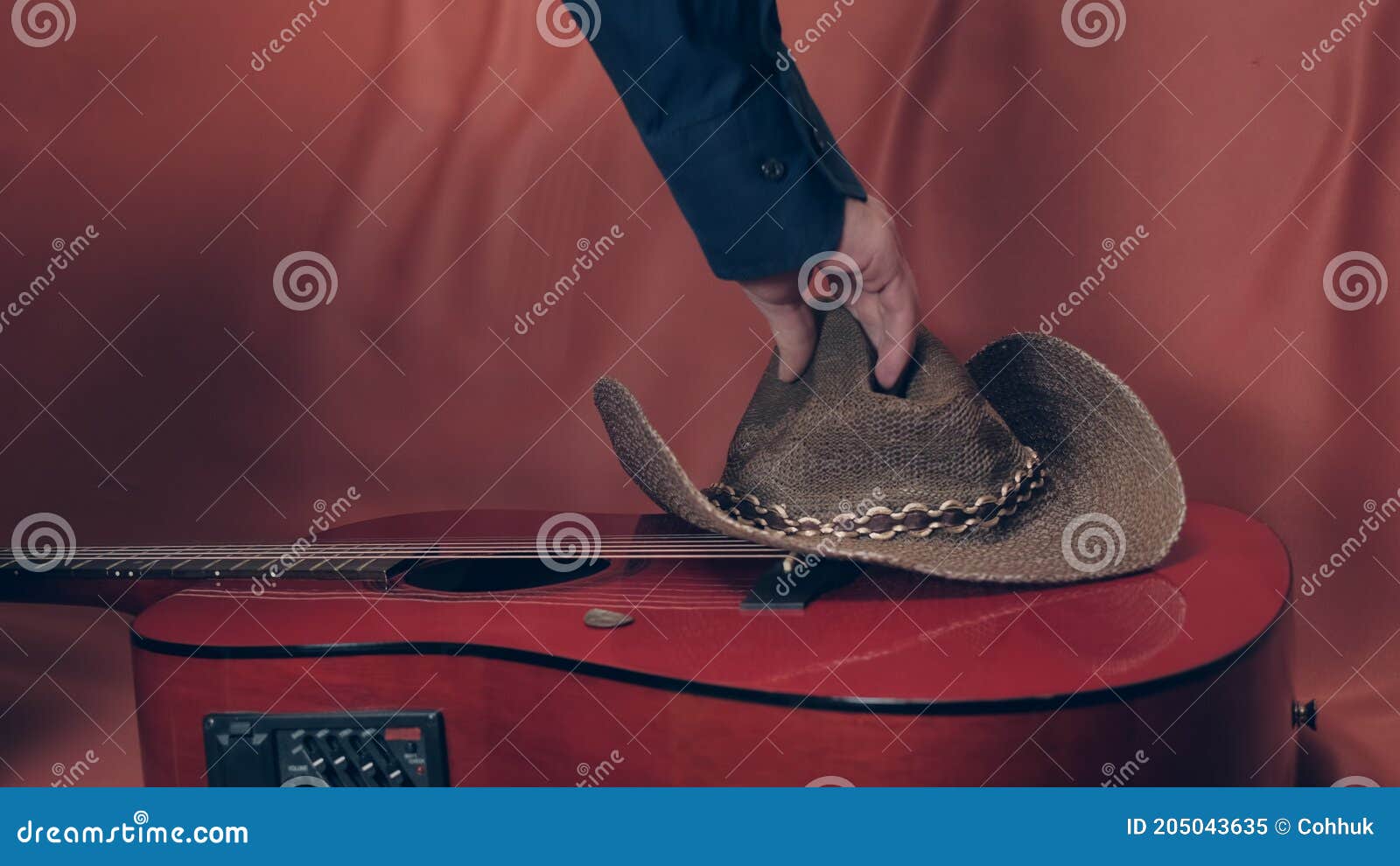 man takes a cowboy hat with red, acoustic guitar
