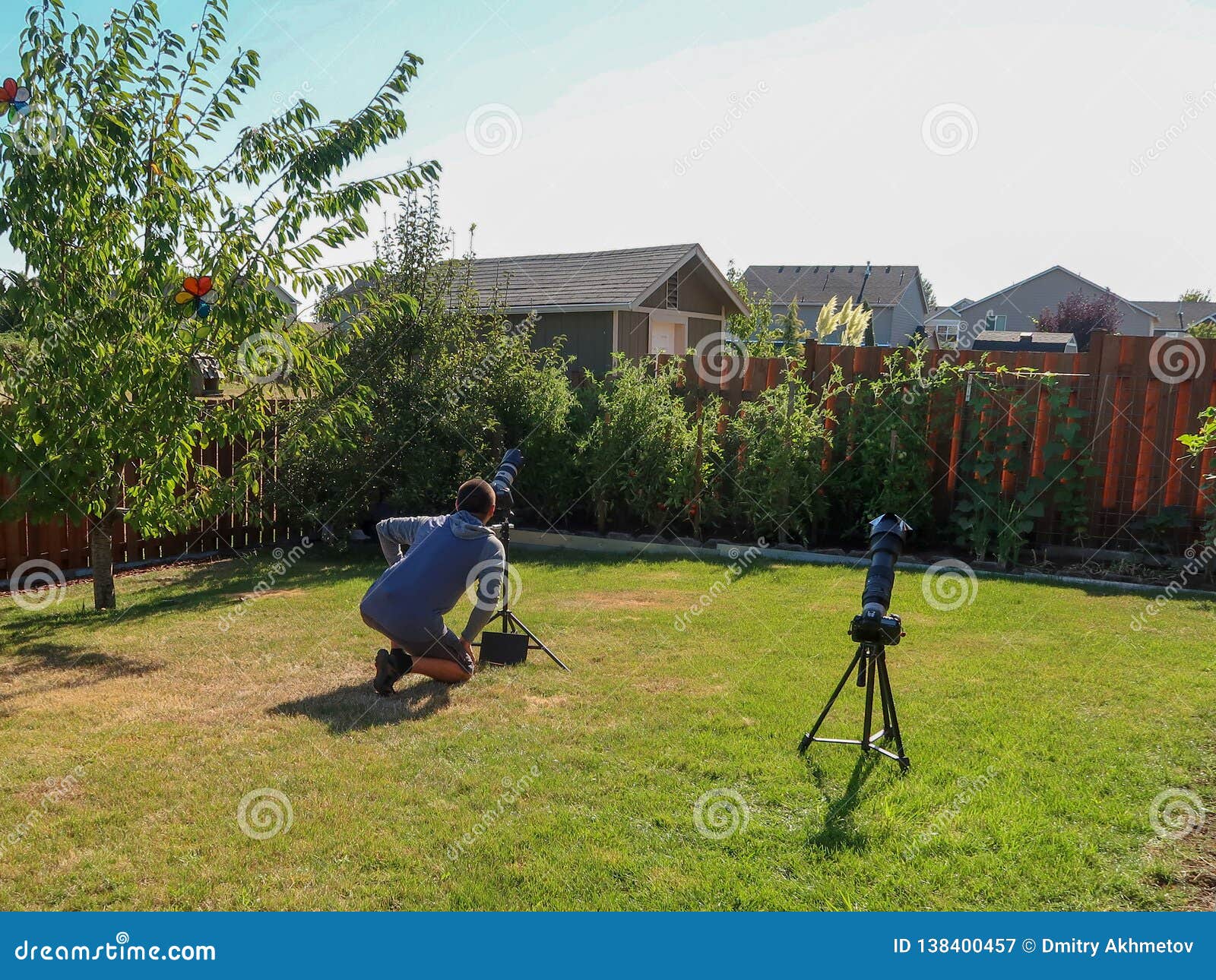 A Man Taking Pictures of a Total Solar Eclipse on a Backyard of House
