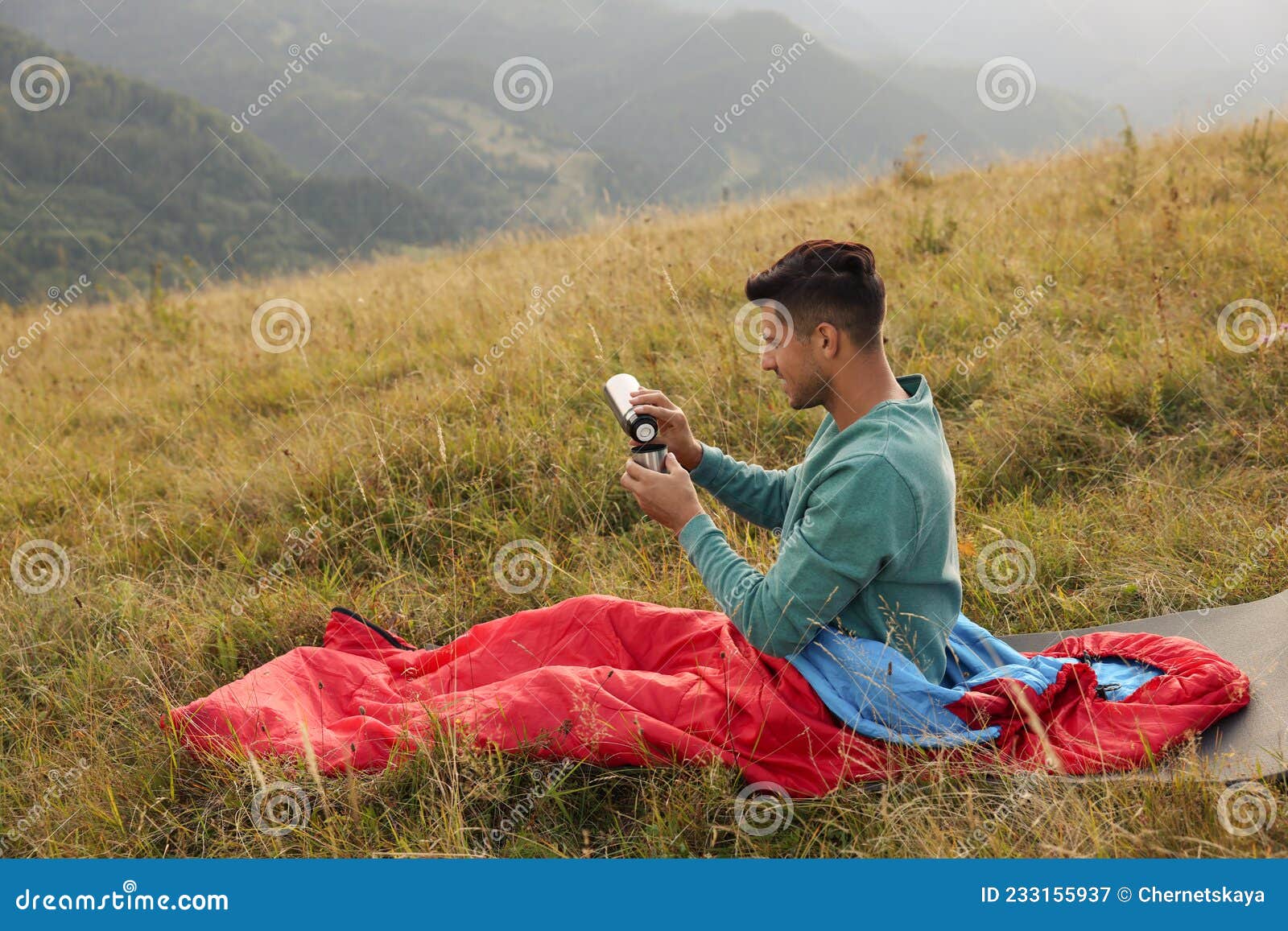 Man with Thermos in Sleeping Bag on Hill, Space for Text Stock Image