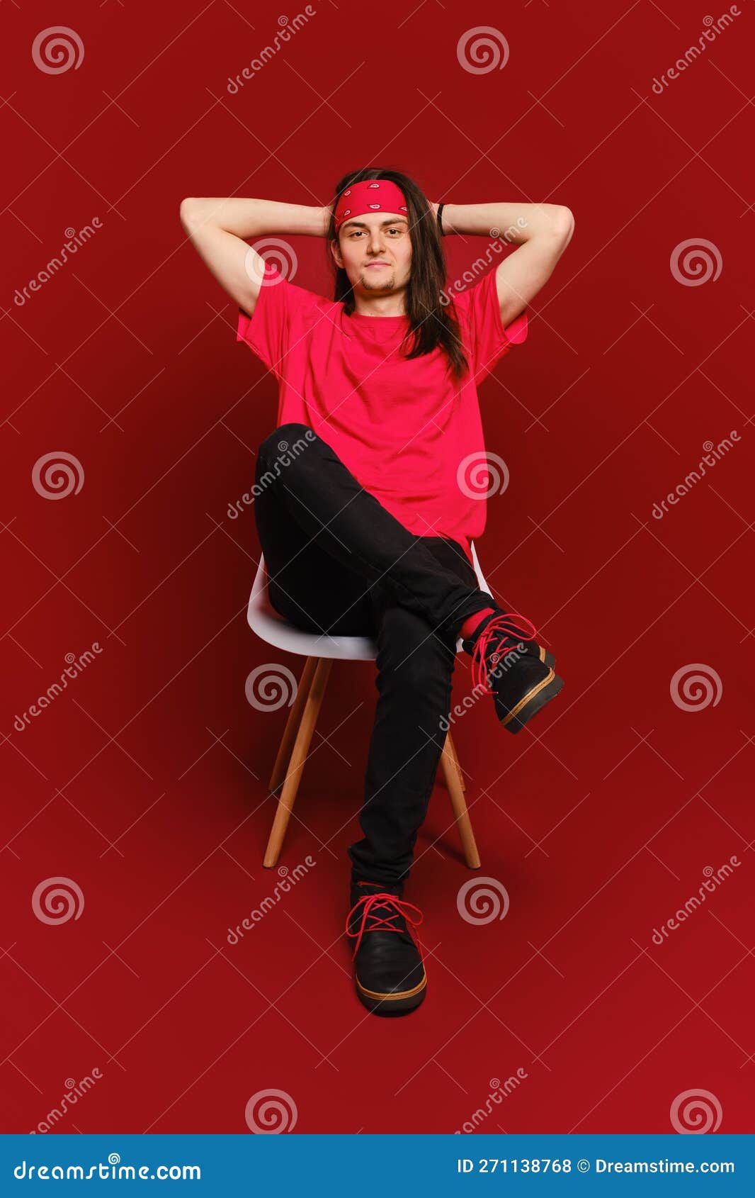 Man Threw His Hands Behind His Head and Sits Relaxed on Chair in Studio