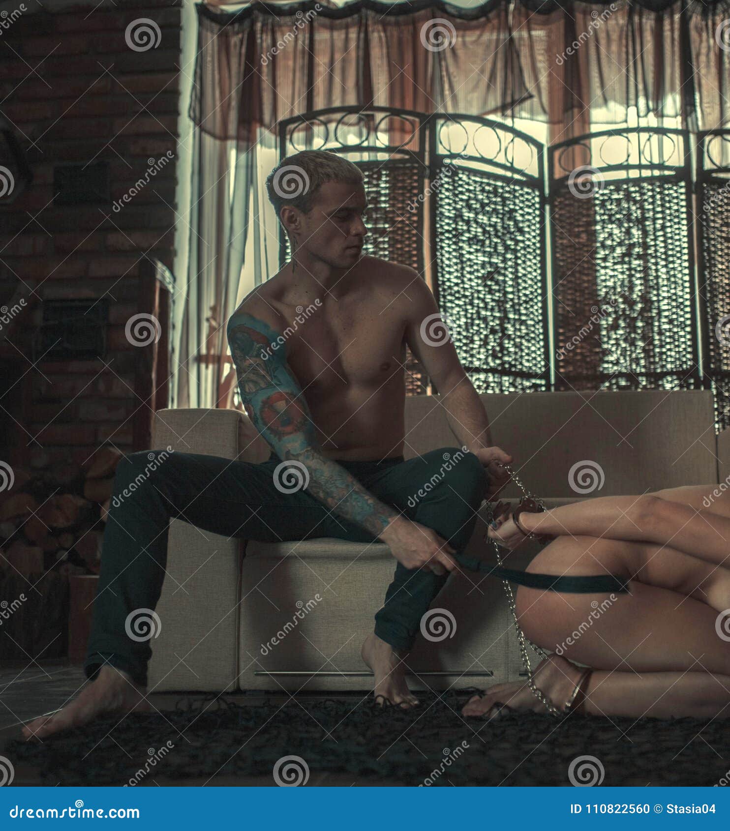 Man Tied the Woman`s Hands and Legs by Chain and Spanks Her by Whip during  a Love Game in Dark Room. Stock Photo - Image of love, nude: 110822560