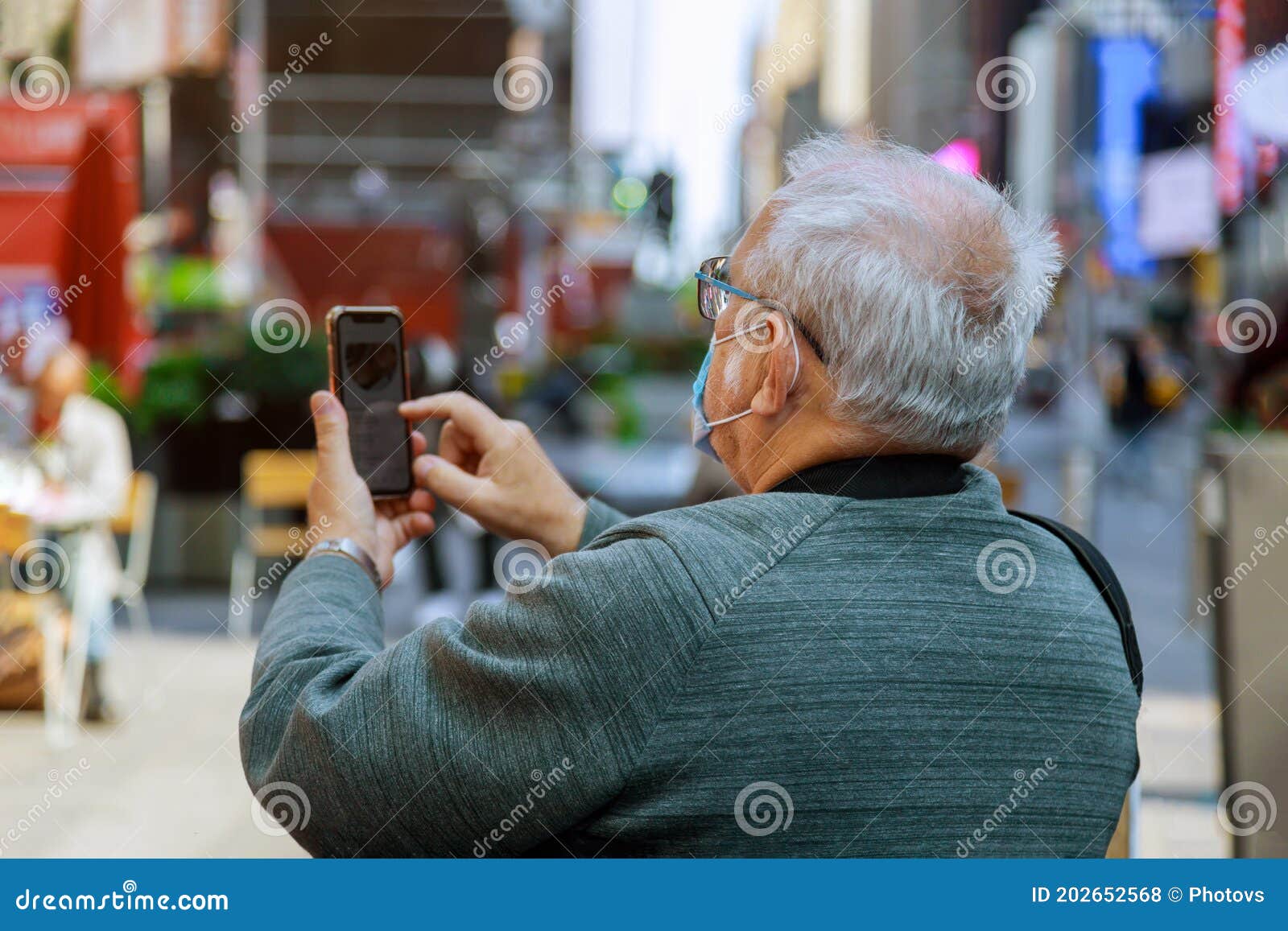 man traveling looking at in smartphone on times square, manhattan, new york city wearing a face mask in covid-19 pandemic season