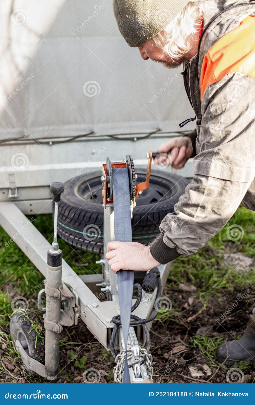 A Man Turns the Trailer Winch on a Trailer, Moving the Load