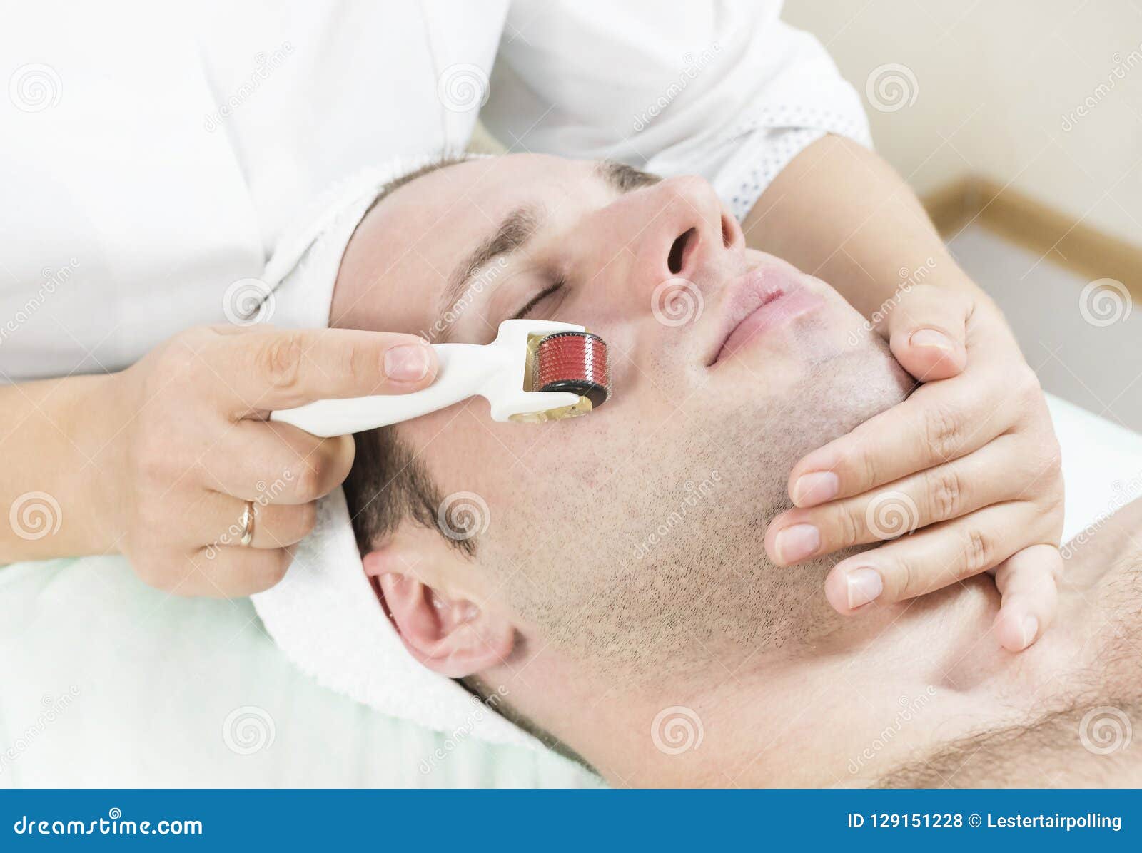 man undergoes the procedure of medical micro needle therapy with a modern medical instrument derma roller.