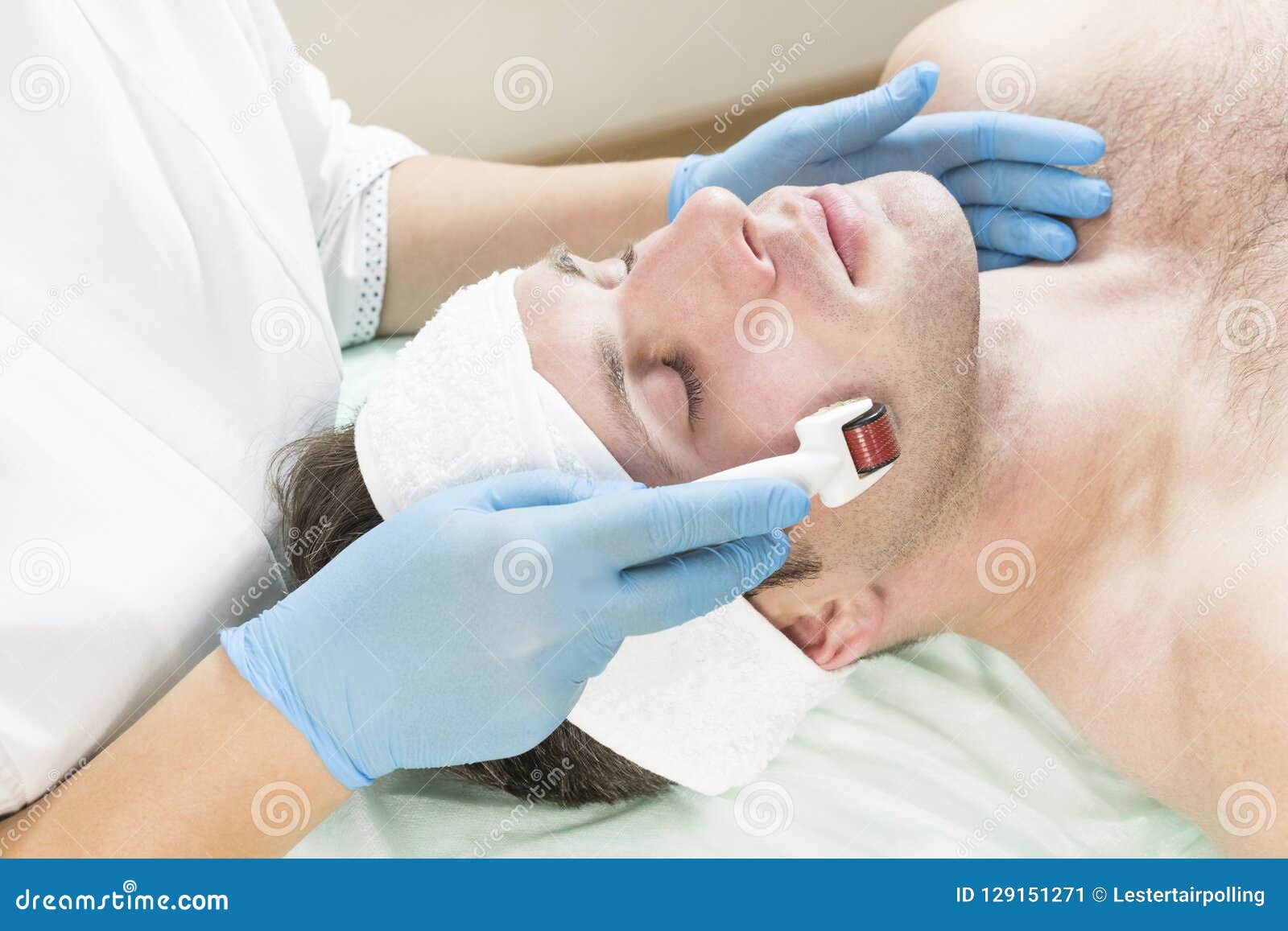 man undergoes the procedure of medical micro needle therapy with a modern medical instrument derma roller.