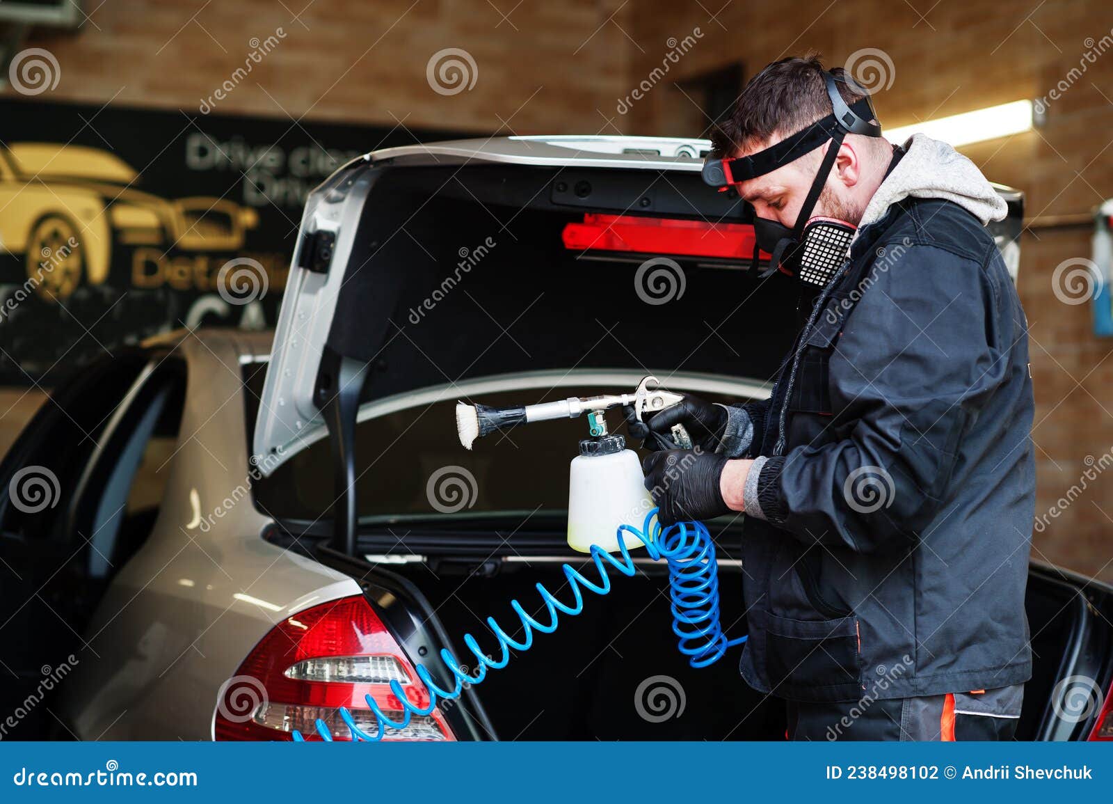 Man in uniform and respirator, worker of car wash center, cleaning