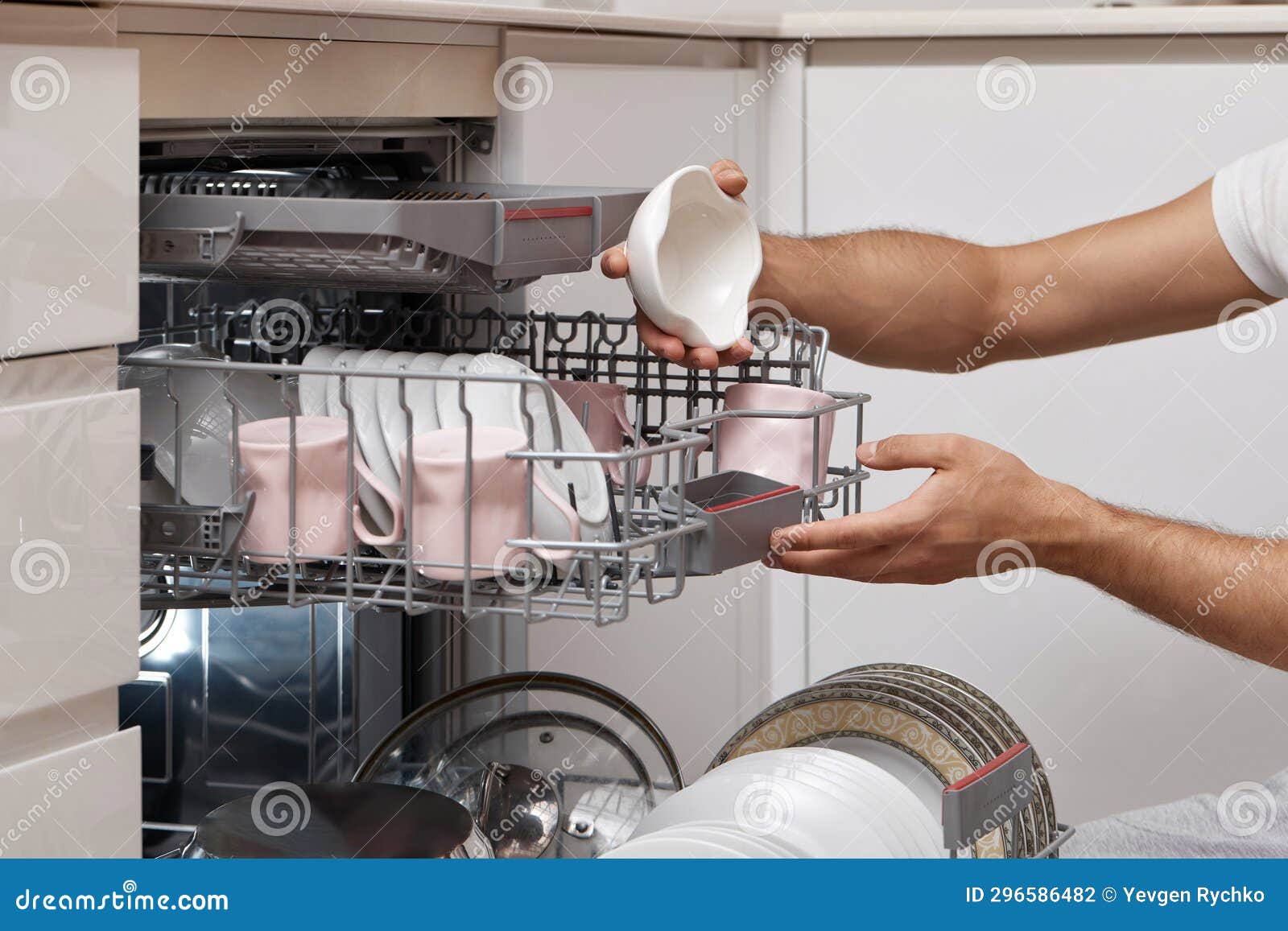 Man Unloading from Open Dishwasher Machine with Clean Utensils Inside