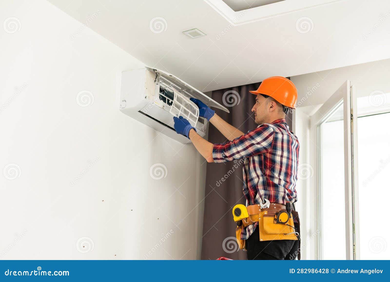 A Man Unscrews an Air Conditioner on the Wall with a Screwdriver. Repair and Maintenance of the