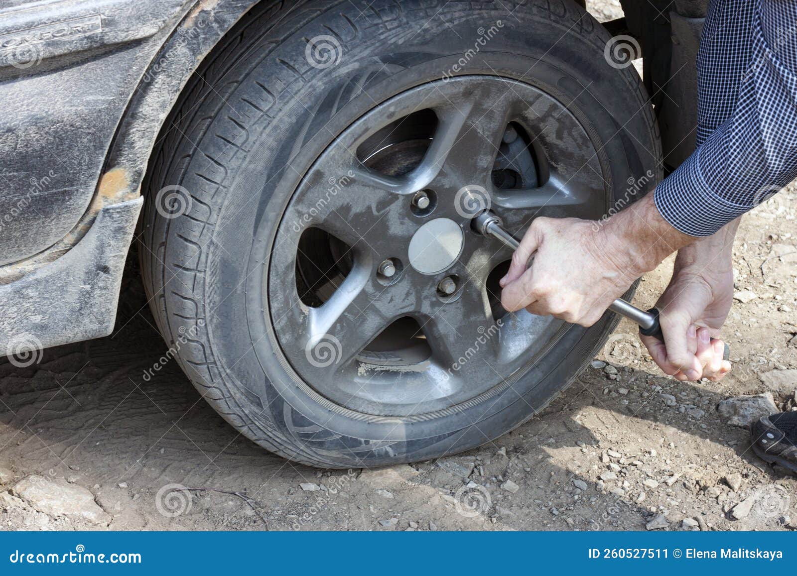 A Man Unscrews a Flat Car Tire Outdoors. Wheel Replacement Stock Image