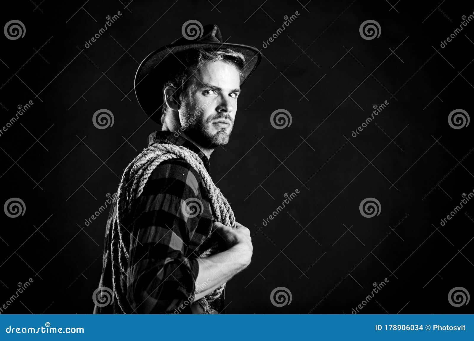 man unshaven cowboy black background. lasso is used in rodeos as part of competitive events. lasso can be tied or