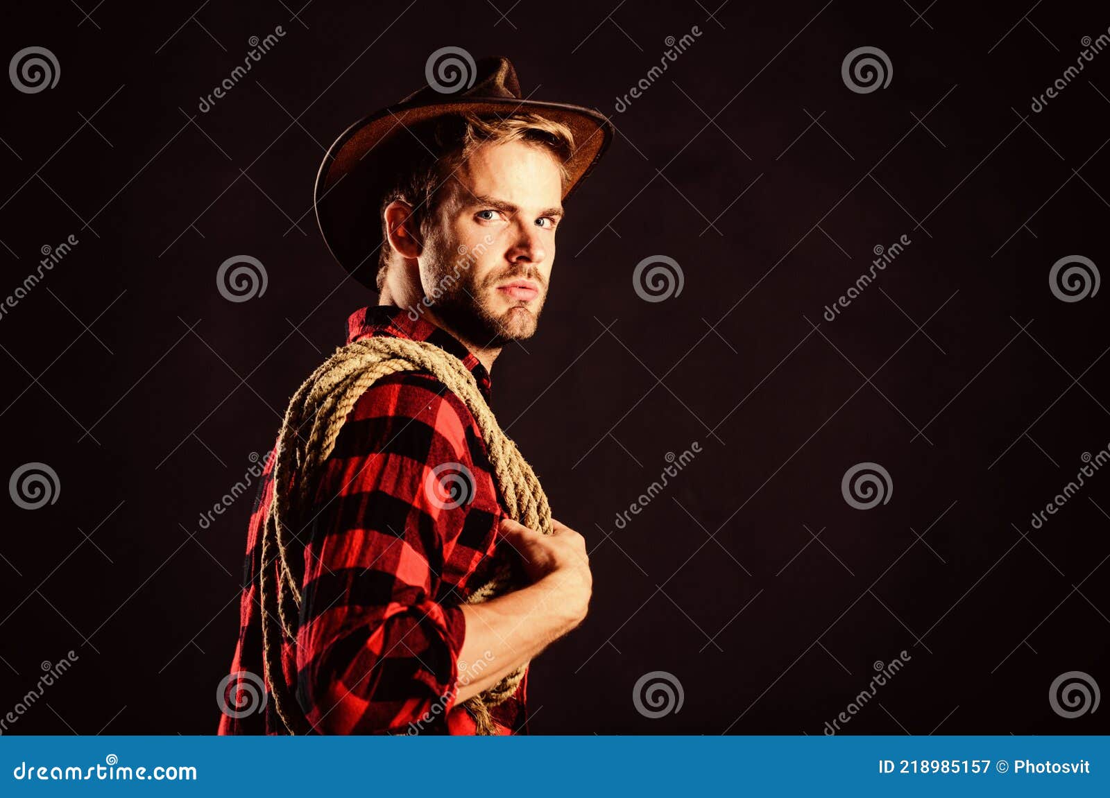 man unshaven cowboy black background. lasso is used in rodeos as part of competitive events. lasso can be tied or