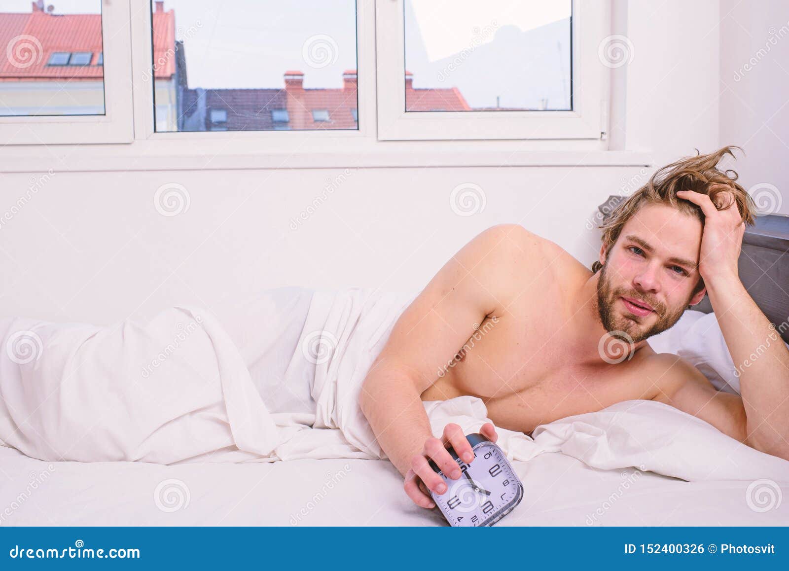 man unshaven lay bed hold alarm clock. man unshaven bearded wakeful face having rest. stick schedule same bedtime wake