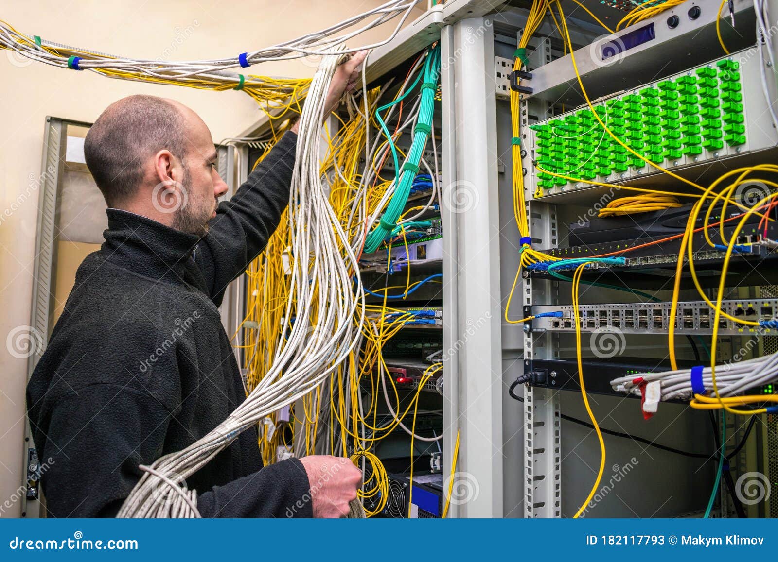 a man untangles many utp wires in racks with computer equipment. specialist switches communication lines in the server room. the t