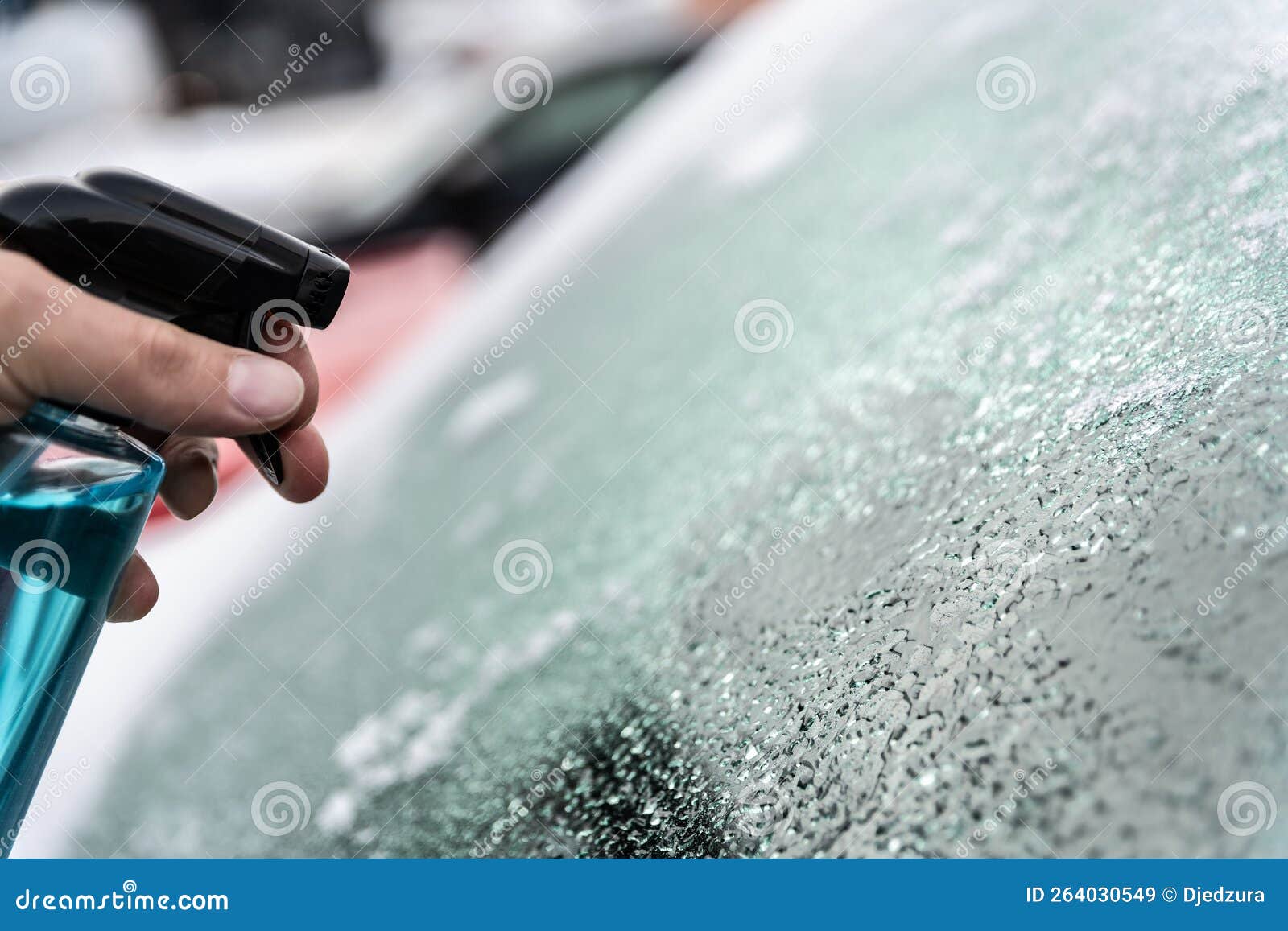 Man Uses a Bottle of Deicer To Defrost the Icecovered Windshield
