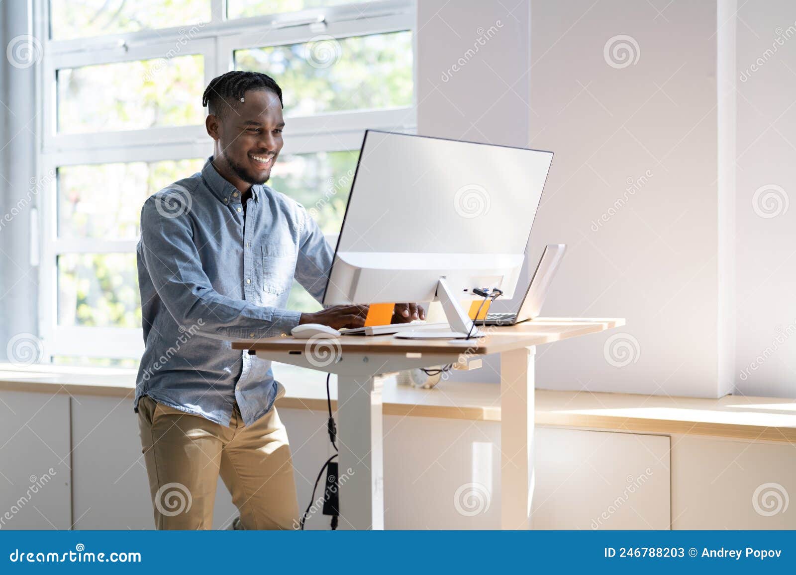man using adjustable height standing desk in office