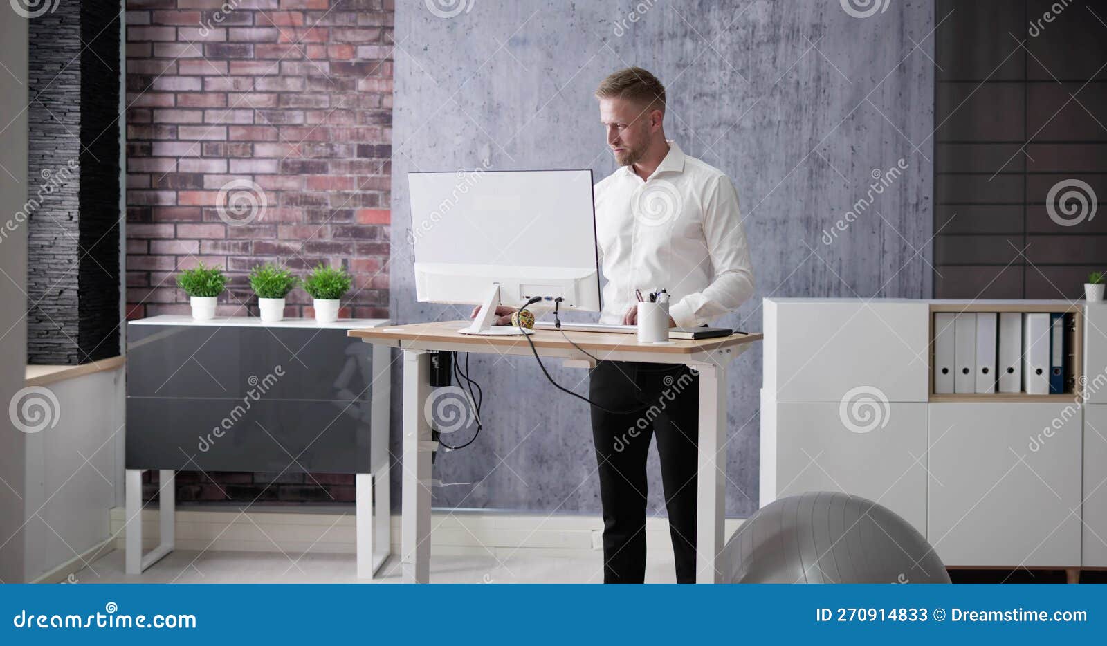 man using adjustable height standing desk in office