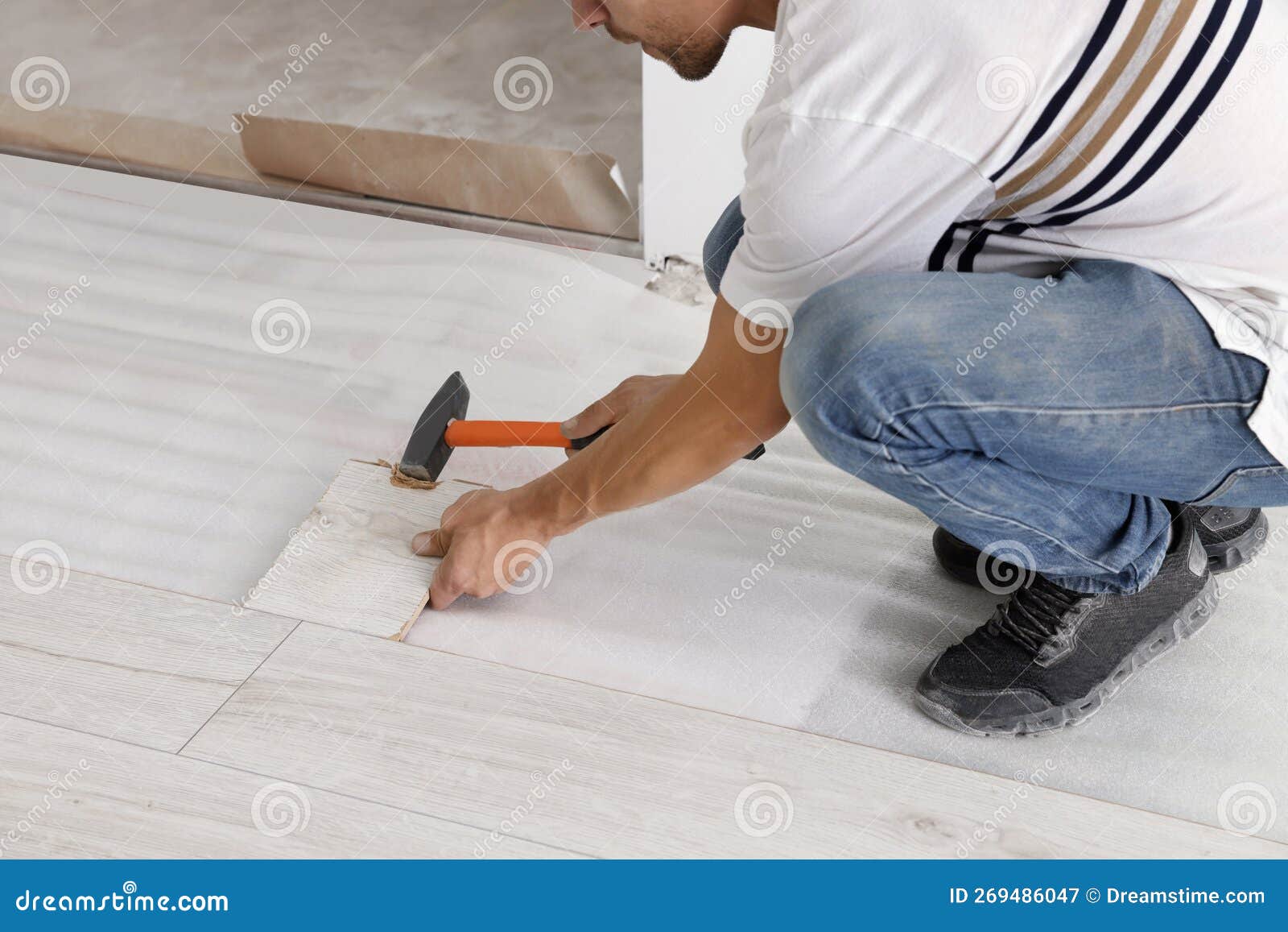 Man Using Hammer during Installation of New Laminate Flooring, Closeup