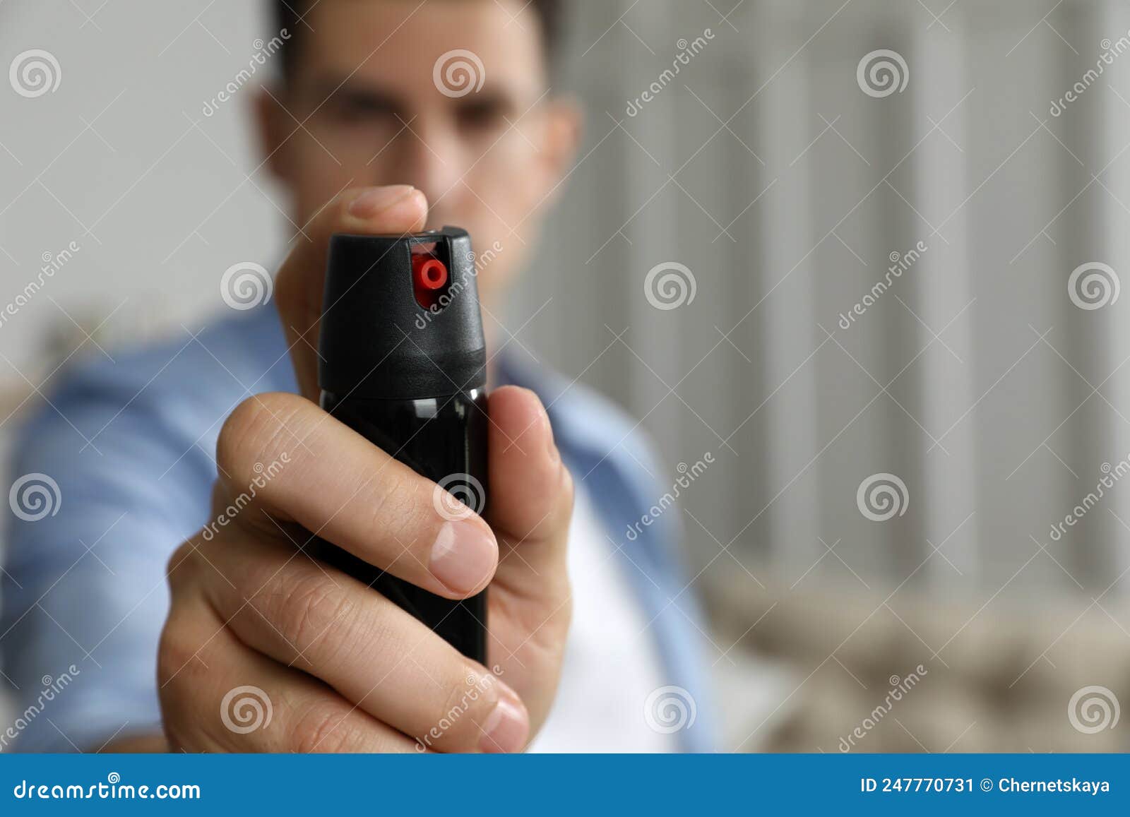 Man Using Pepper Spray at Home, Focus on Hand. Space for Text Stock