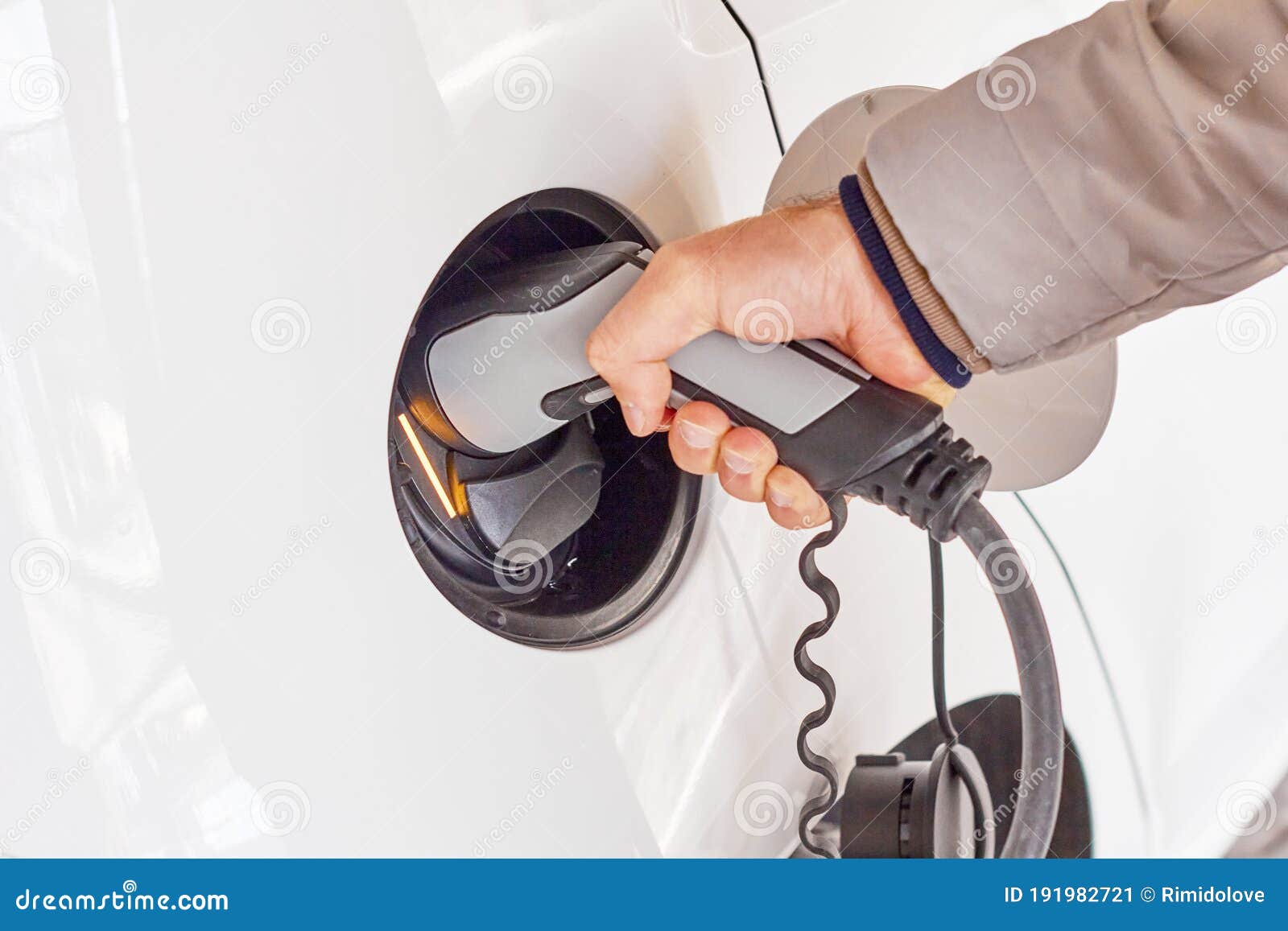 Man Using a Power Cable and Plug for Charging of Electric Car at EV