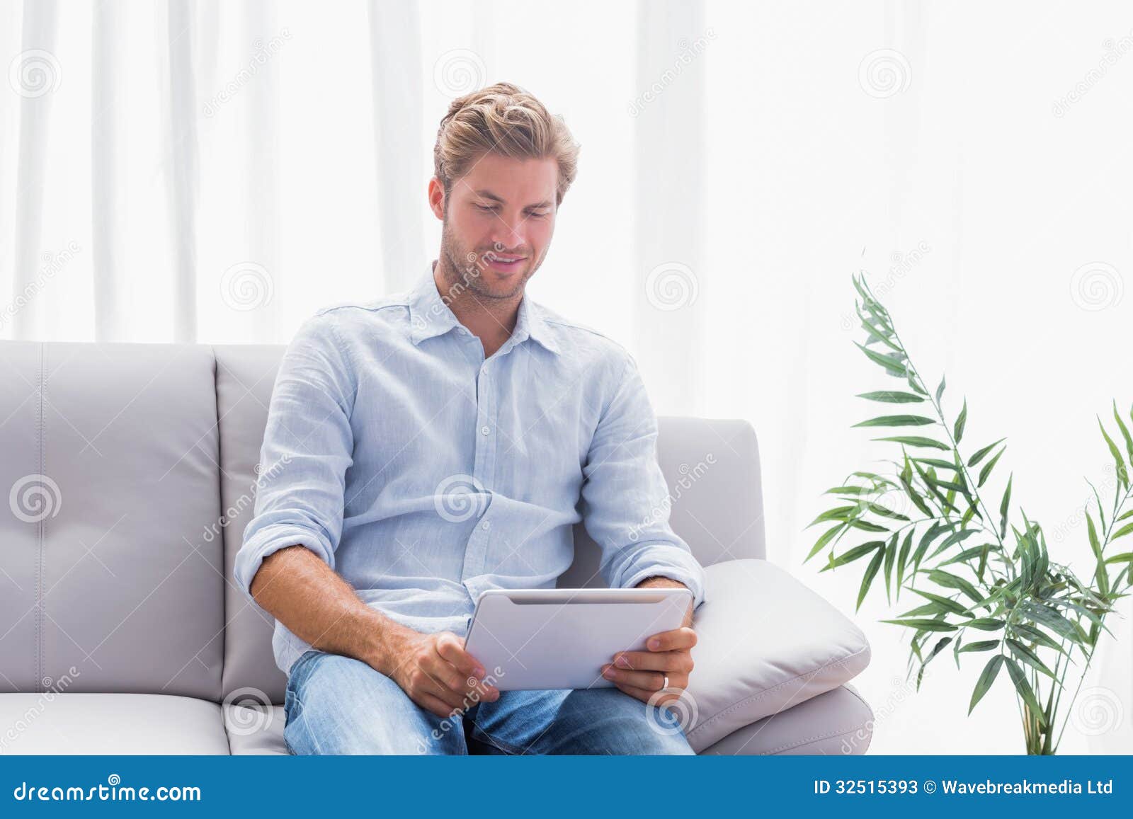 Man Using A Tablet While He Is Sat On The Couch Stock Image Image Of Blonde Attractive