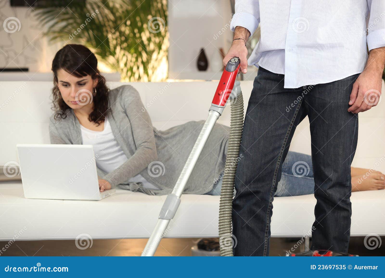 Man vacuuming and a woman working on her laptop