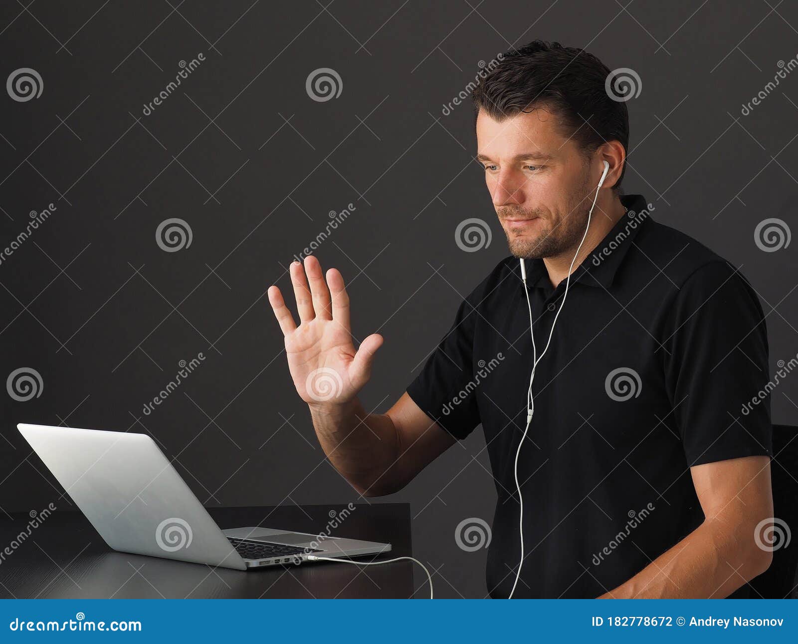 man in video conferencing call via laptop and greeting colleagues.