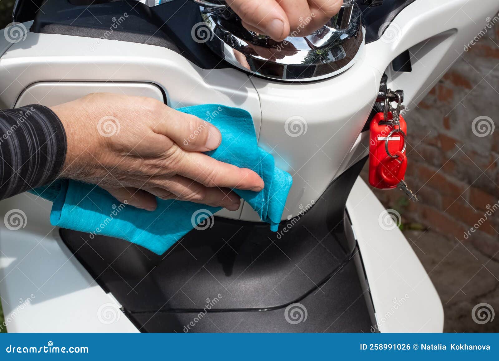 A Man Washes the Front of a Scooter with a Rag. Maintenance and Care of Motorcycles Stock Photo