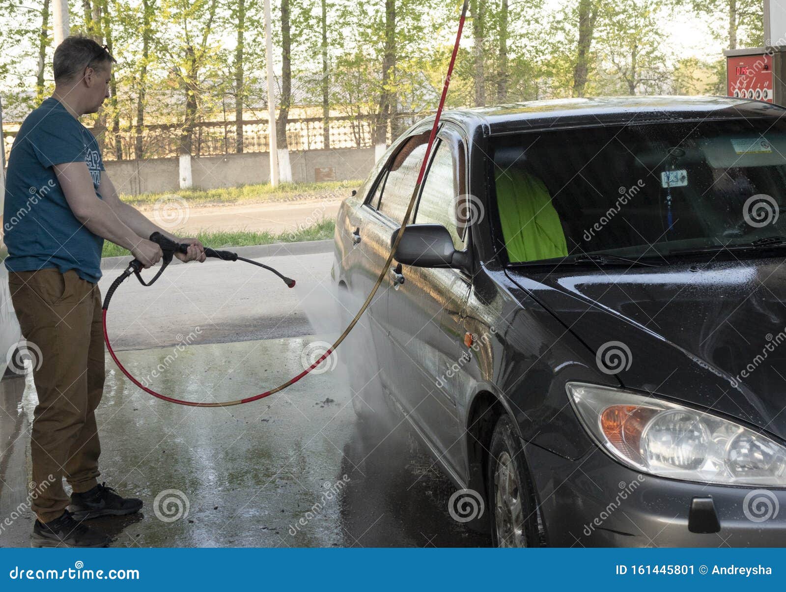 a man washes his car with pressurized water in a car wash