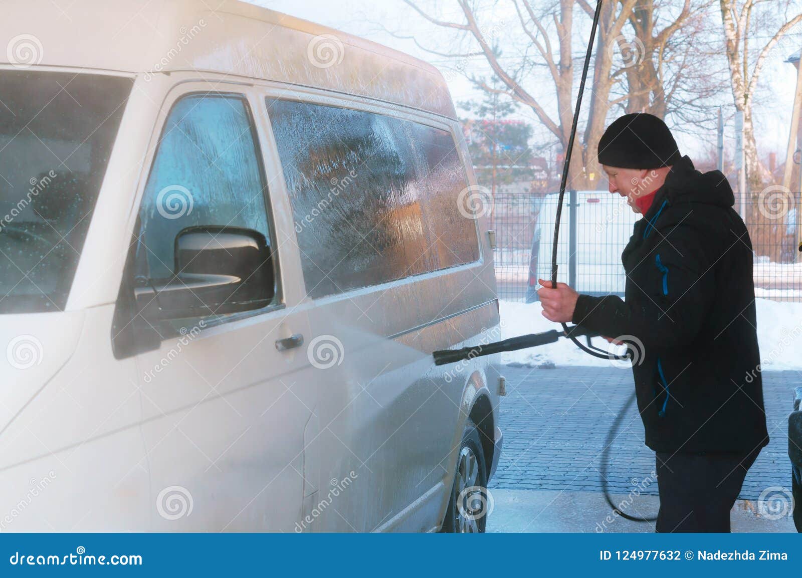 A Man Washes a Van at a Car Wash in the Winter, a Man Washes a White