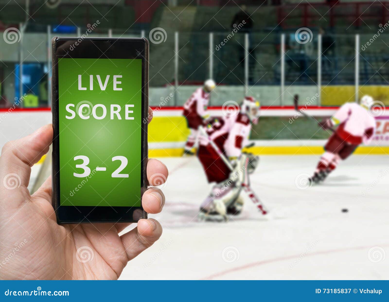 Man is Watching Ice Hockey and Holds Smartphone in Hand with Live Score Stock Image
